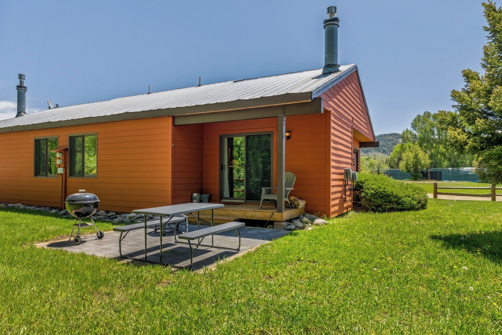 A modern house with a covered patio, a barbecue grill, and a dining table.