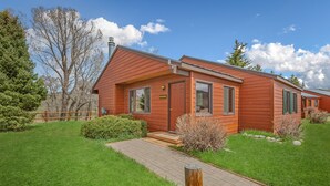 Une maison en bois d’un seul étage, dotée d’un porche à l’avant, d’une allée pavée et d’une pelouse bien entretenue.