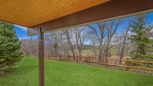 Une terrasse en bois donnant sur une courClose et des arbres.
