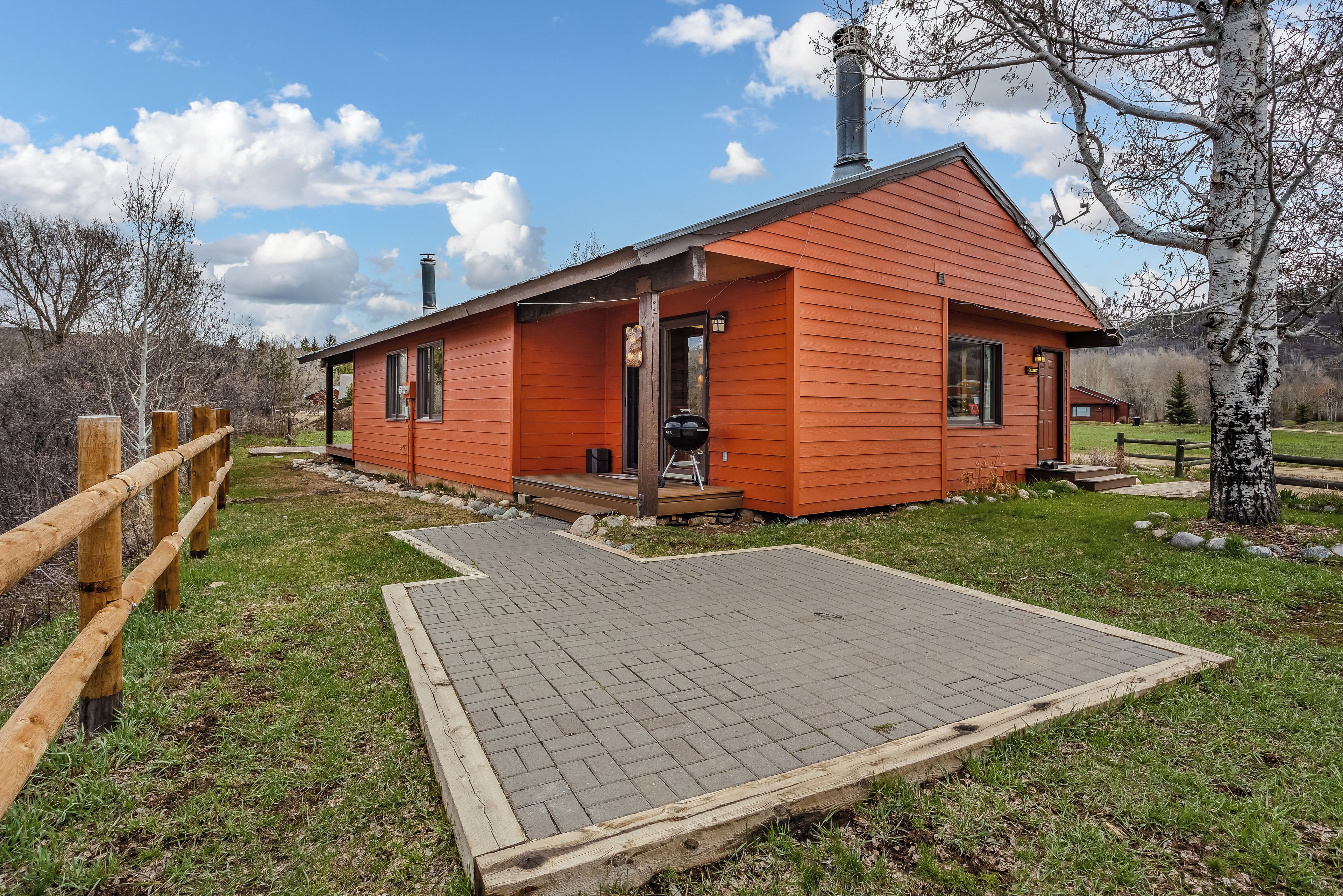 En liten, envåningsbyggnad med en röd fasad och en innergård i tegel som leder fram till entrén.