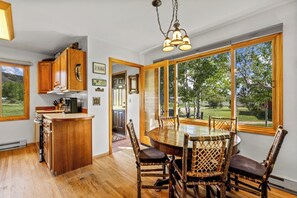 Een keuken met houten kasten, een bar en een eettafel met stoelen.