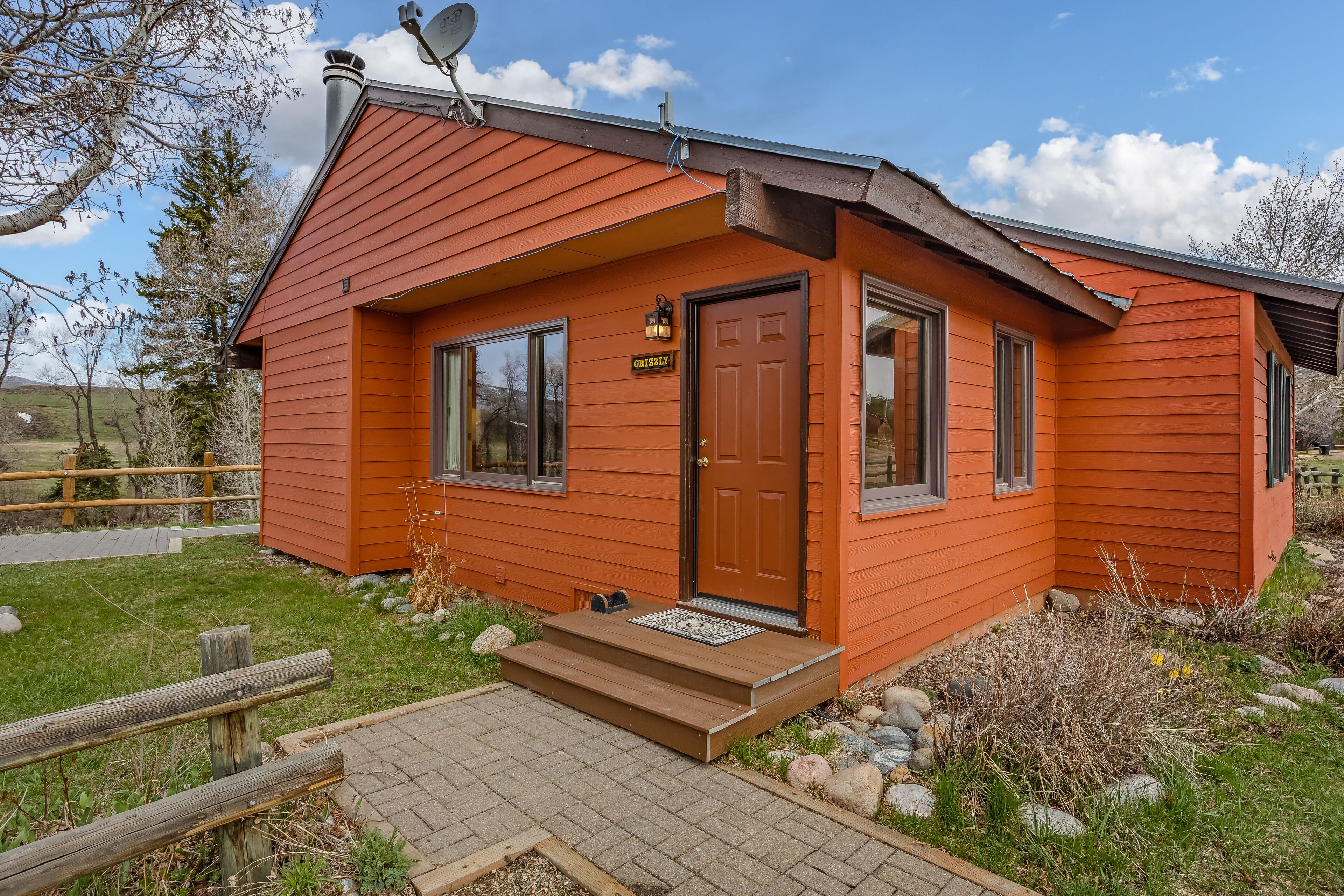 A small, single-story house with a red exterior, a front door, and a small porch.