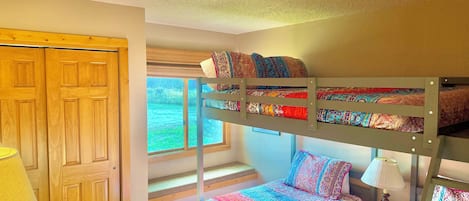 Dormitorio con literas, ventana, puerta de madera y lámpara.
