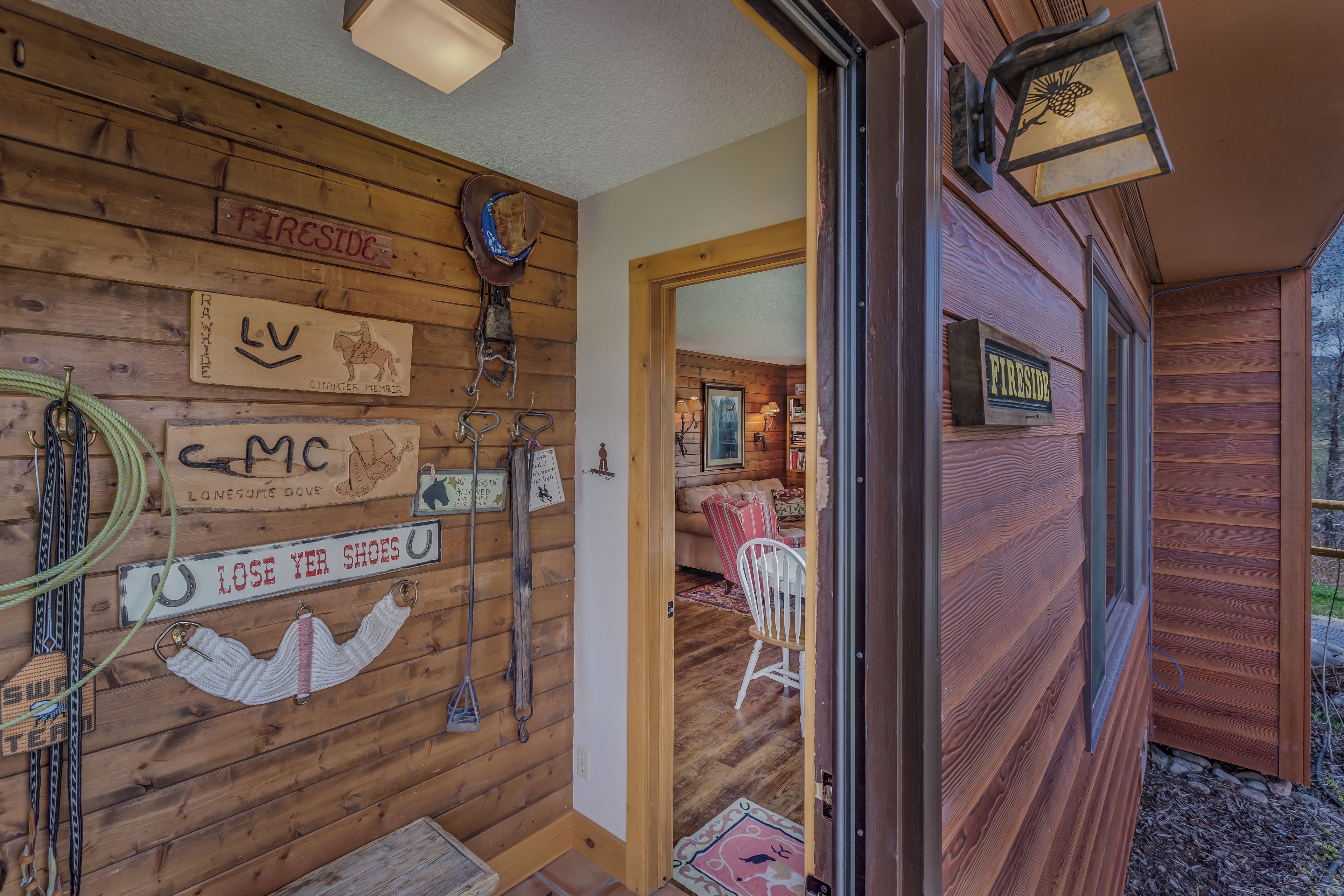 A wooden cabin interior with a mounted sign reading "Fireside," a horse head decoration, and a sign indicating "Lost Your Shoes."