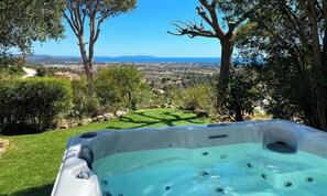 Un jacuzzi con vistas despejadas al paisaje, incluyendo árboles, césped y colinas distantes.