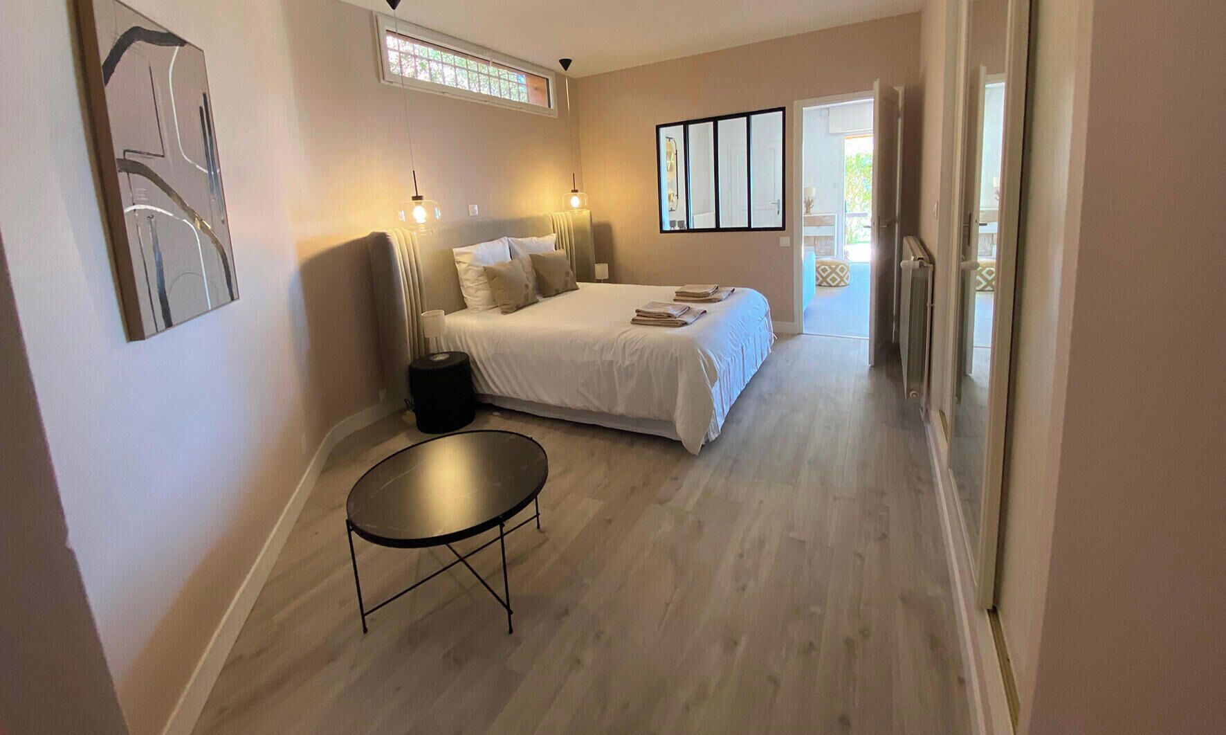 Een slaapkamer met een bed, nachtkastjes, een ronde tafel en een raam.
