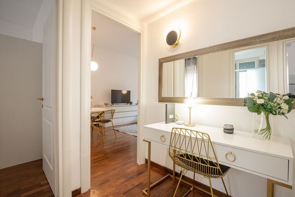 Een moderne badkamer met een grote spiegel, een wastafelmeubel, een gouden stoel en een bureau met een lamp.