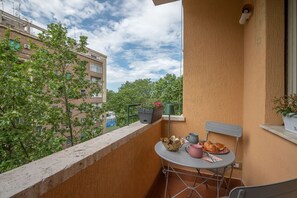 Un balcon avec une table, des chaises et des plantes en pot.