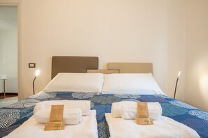 A hotel room with a bed, two bedside tables, and a nightstand with a lamp. - Sweeties apartment san Giovanni (Roma)