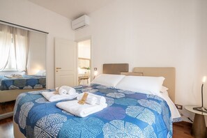 Une chambre d’hôtel équipée d’un lit, d’un miroir, d’un climatiseur et d’une table de chevet avec une lampe.