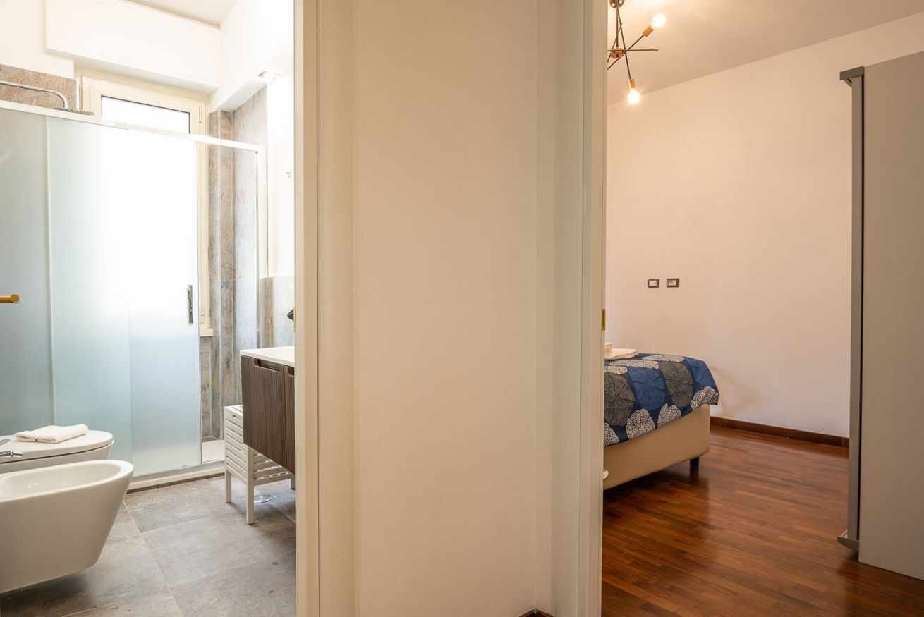 A modern bathroom with a glass shower enclosure, a white bathtub, and a toilet.