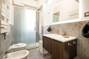 Une salle de bain moderne dotée d’une douche à parois de verre, d’un lavabo sur pied et d’un meuble-vasque avec des placards.