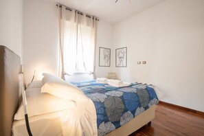 Une chambre à coucher avec un lit, une fenêtre avec des rideaux et deux tableaux accrochés au mur.