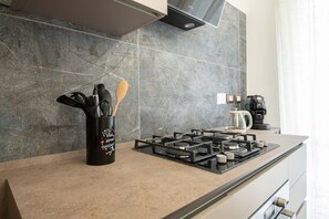 A modern kitchen with a gas stove, a coffee maker, and a utensil holder on the counter. - Sweeties apartment san Giovanni (Roma)