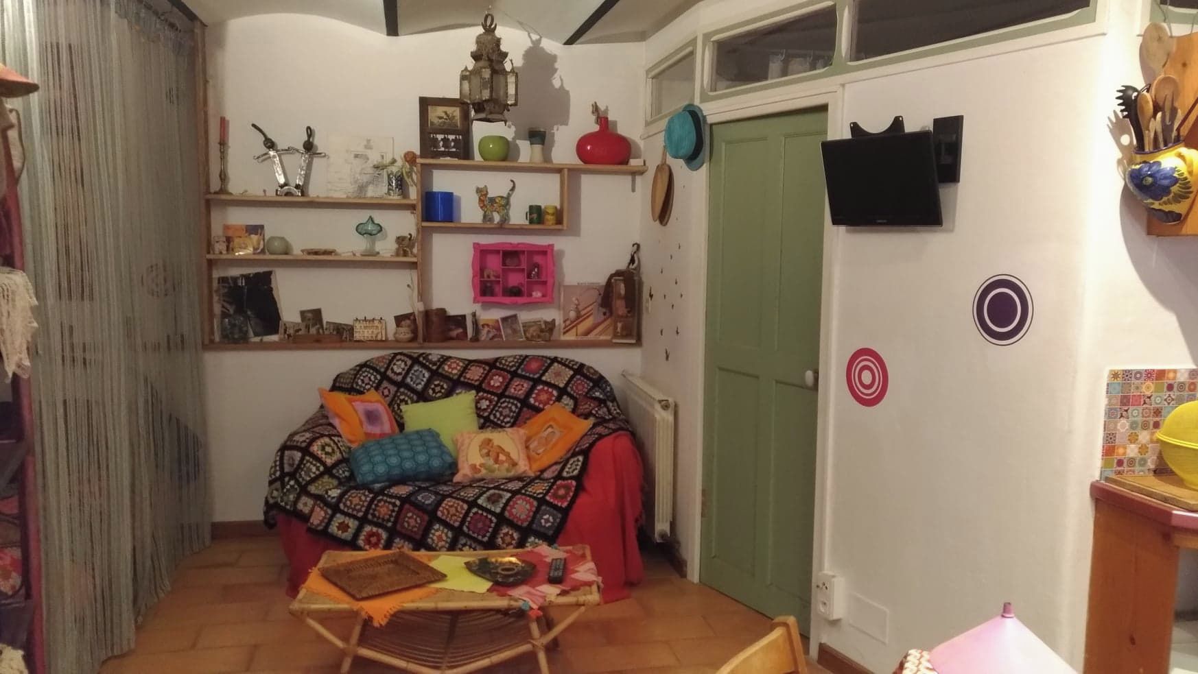 A cozy room with a patterned sofa, a small table with items, and a green door.