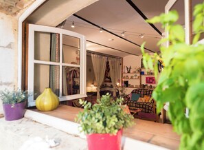 A cozy living room with a large window, a sofa, a small table, and various decorations.