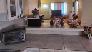 A kitchen with a toaster, a coffee machine, and a television in the background. - Comfortable Home in Hallandale Beach (Hallandale beach)