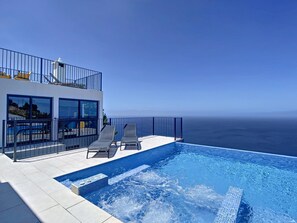 A modern building with a rooftop pool overlooking the ocean.