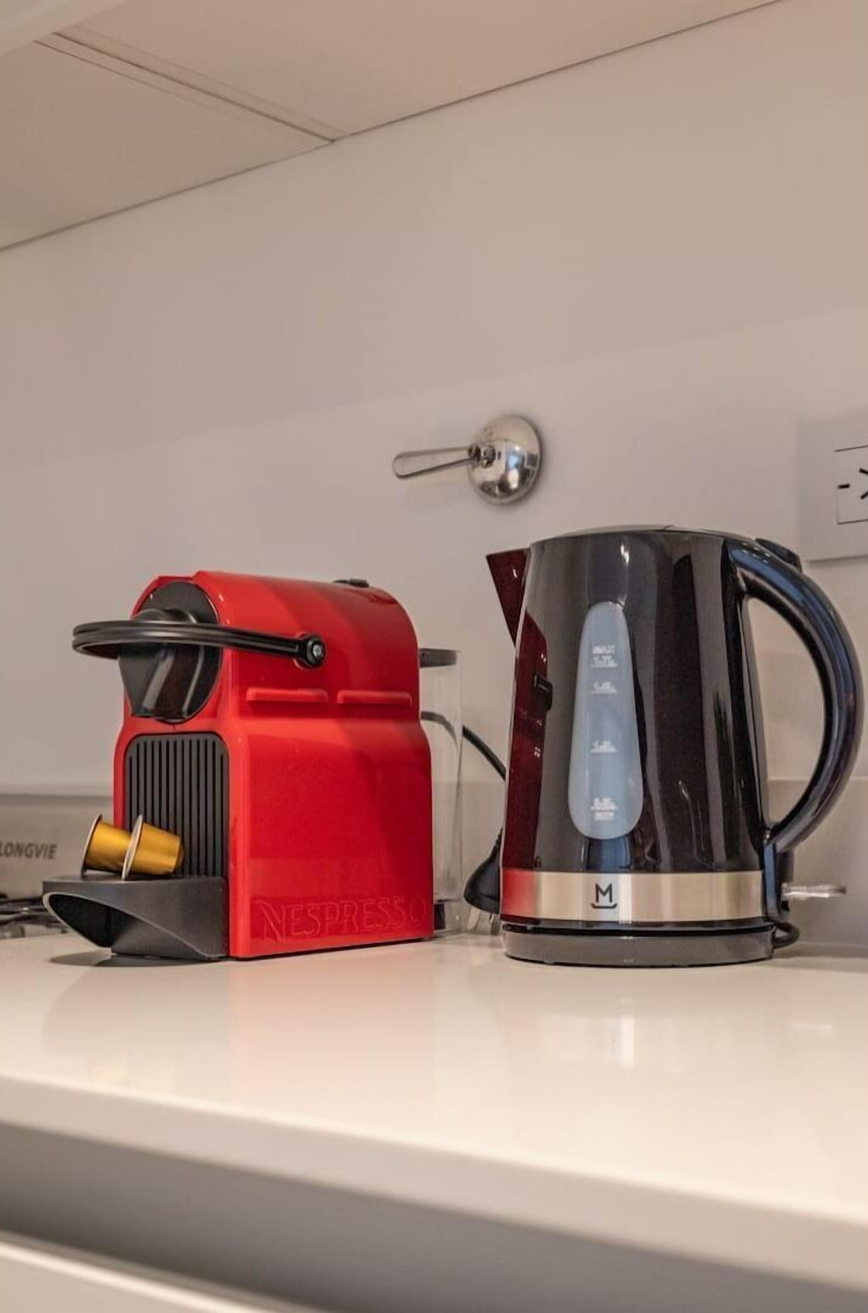 A red Nespresso machine and a black coffee maker on a white countertop.