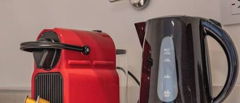 A red Nespresso machine and a black coffee maker on a white countertop.