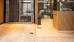 Un moderno vestíbulo de hotel con mostrador de recepción, un área de espera con asientos y un amplio puerta de vidrio que da al acceso.