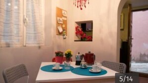 A dining area with a table set for two, a bulletin board, and a small window with a view of a snowy landscape. - Vaticanhouse  (Roma)