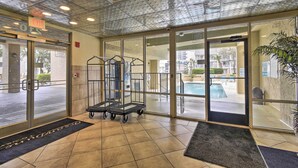 A hotel lobby with a glass door entrance, a pool visible through the door, and a metal cart near the entrance. - Myrtle Beach Condo w/ Ocean View + Pool Access! (Myrtle Beach)