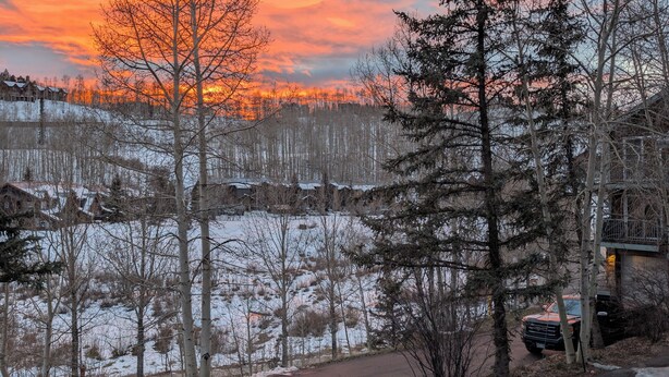 A view from a balcony overlooking a snowy landscape with a sunset.