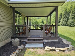 A covered porch with outdoor furniture, a stone pathway, and a well-maintained lawn.