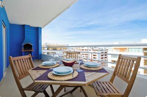 Ein Balkon mit einem Tisch für vier Personen, Stühlen und einem Grill.
