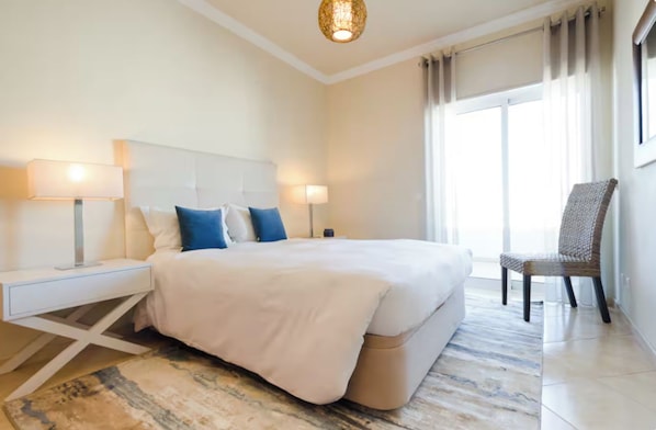 A hotel room with a large bed, bedside lamps, a chair, and a view of the outdoors.