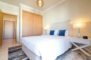 Quarto de hotel com uma cama grande, luminárias laterais, guarda-roupa e um moderno candeeiro de teto.