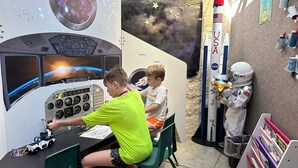 Ett rum med rymdtema, utrustat med en kontrollpanel, en modell av en raket och figurer föreställande astronauter.