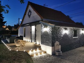 A house with a stone exterior, a wooden deck, and a small outdoor seating area.