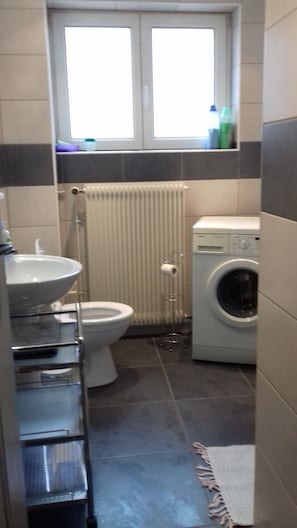 A compact bathroom with a toilet, sink, and washing machine.
