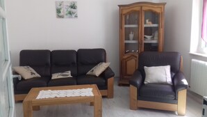 Una sala de estar con un sofá, un mueble de madera y una mesa de centro.