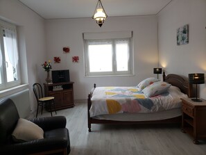 A bedroom with a bed, a chair, a desk, a lamp, and a window.