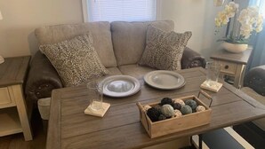 A cozy living room with a sofa, a wooden coffee table, and a side table with decorative items. - Country View Cottage-Near Massanutten, Skyline drive,&JMU.A home away from home! (Elkton)