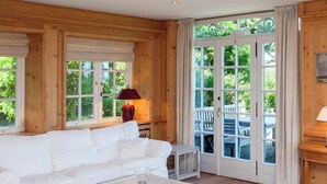 A room with a white sofa, a small table, and a door leading to an outdoor area with a table and chairs.
