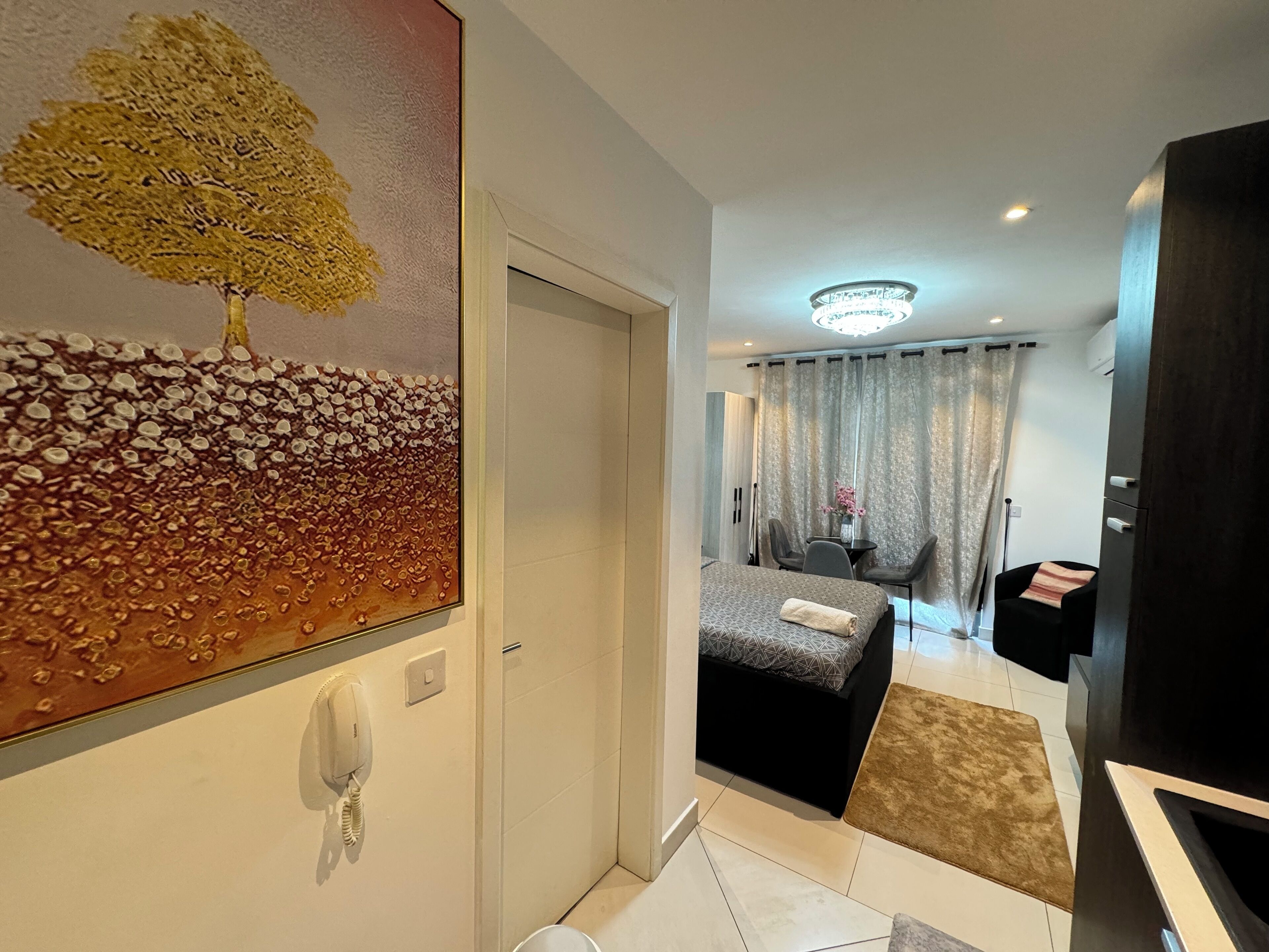 Ein Hotelzimmer mit Bett, Schreibtisch, Stuhl, einem Bild und einem Telefon.