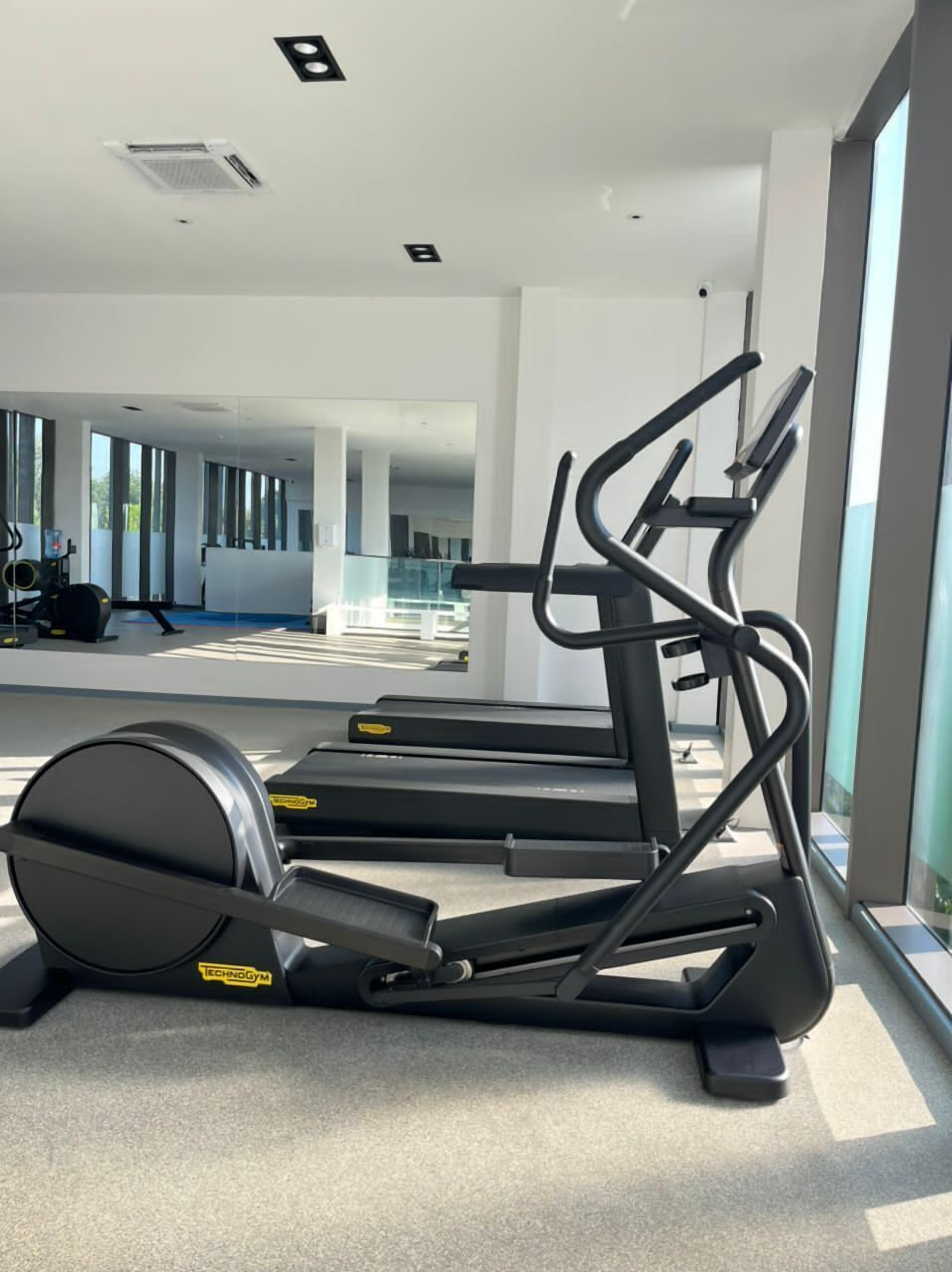 A gym with treadmills and exercise equipment, large windows, and a modern interior design.