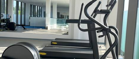 A gym with treadmills and exercise equipment, large windows, and a modern interior design.