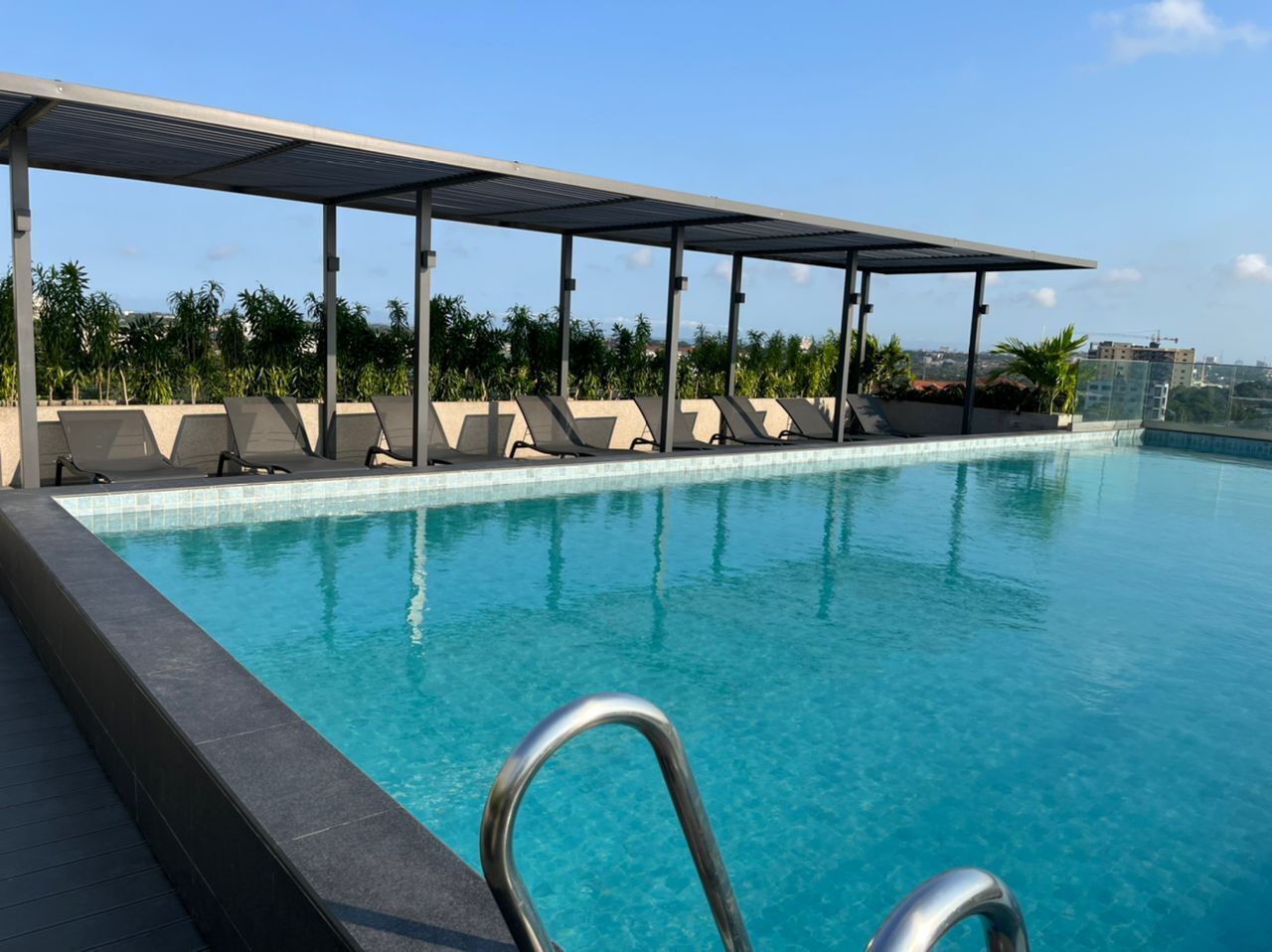 Une piscine dotée d’un espace de repos couvert et de chaises longues.