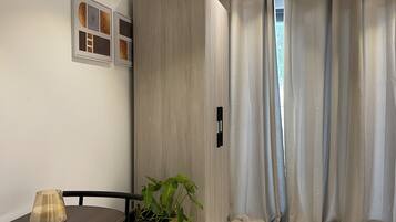 Una sala moderna con una mesa de comedor, sillas, una planta en maceta, un armario y un ventanal con cortinas.