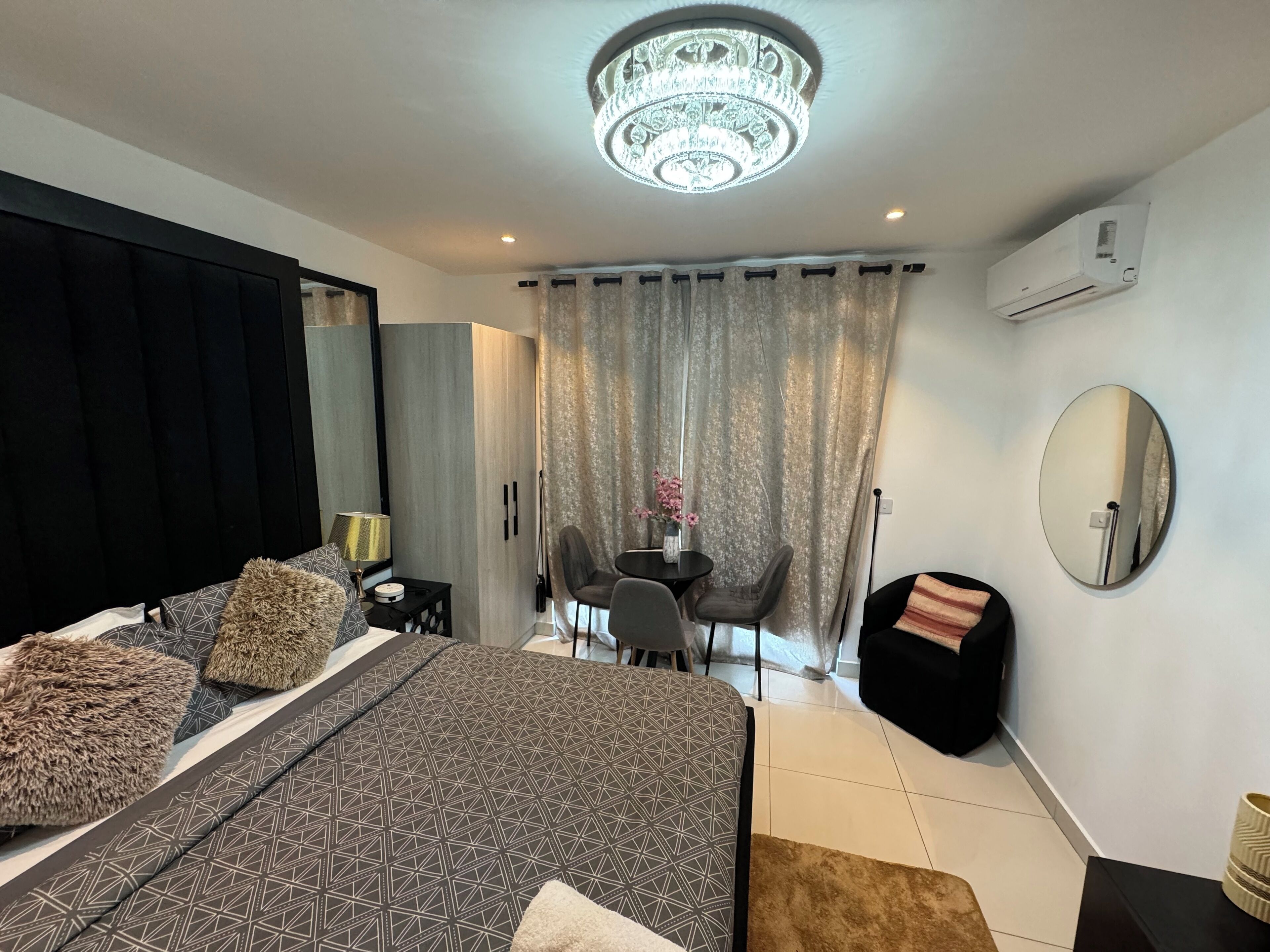 Un dormitorio moderno con una cama grande, un escritorio, una silla y una araña.
