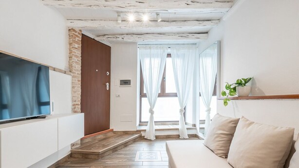Un salon moderne avec un téléviseur à écran plat, un canapé et un escalier menant à un balcon.