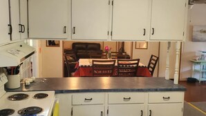 A kitchen with white cabinets, a stove, and a dining area with a table and chairs.