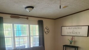 A living room with a grey sofa, a small table with a vase, and a sign on the wall.