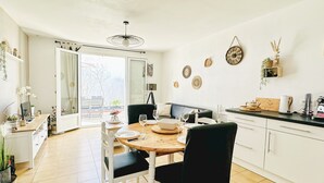 A dining area with a wooden table, white chairs, and a black sofa. There are decorative plates on the wall and a small plant on the counter. - Renovated house and tastefully decorated in La Chaume (Les Sables-d´Olonne)