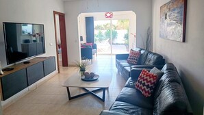 Ein modernes Wohnzimmer mit Flachbildfernseher, Ledersofa und Couchtisch.